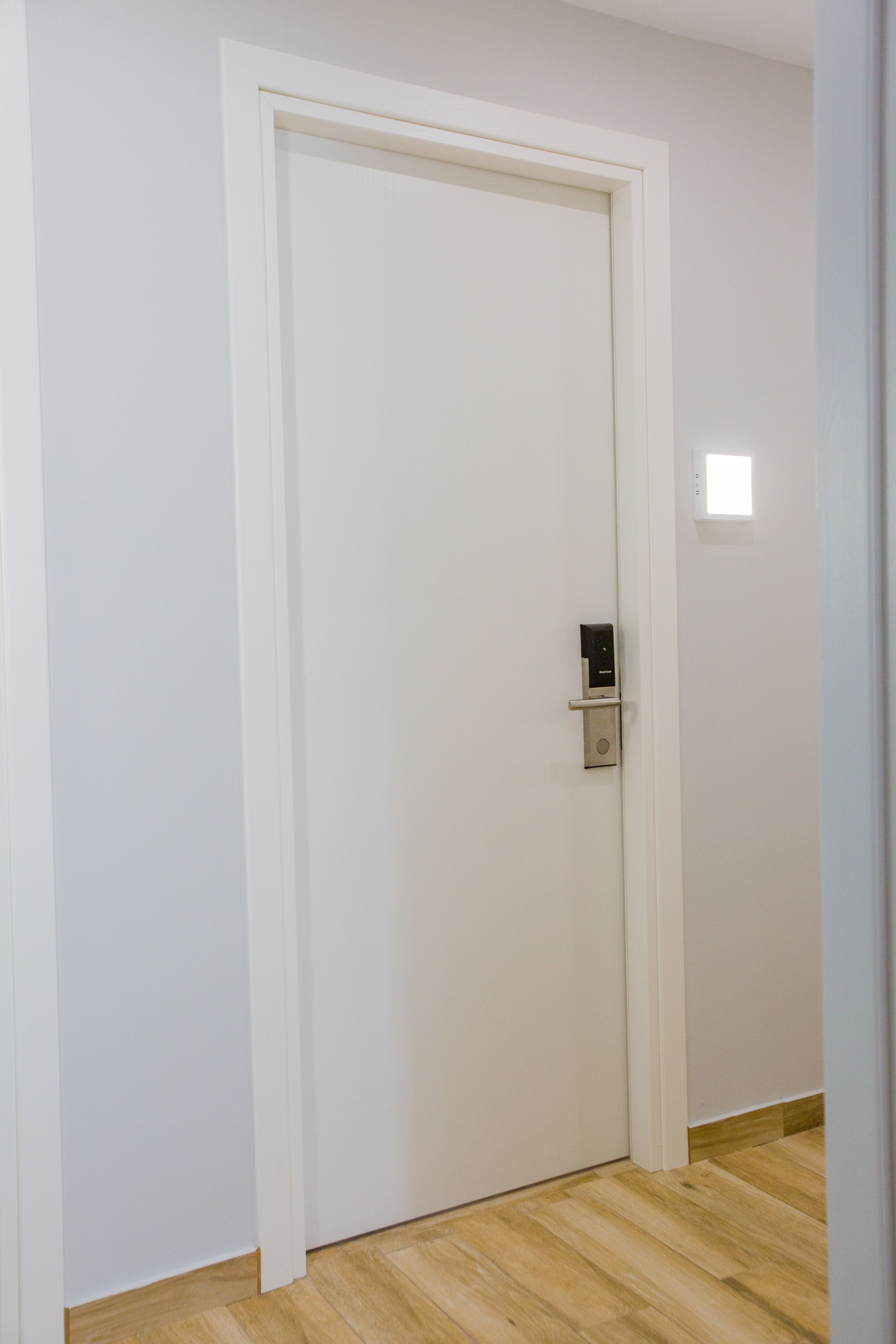 A closed door with a modern lock and a small light switch on the wall.