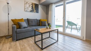 Una sala de estar moderna con un sofá gris, una mesa de centro de madera y una lámpara de pie.