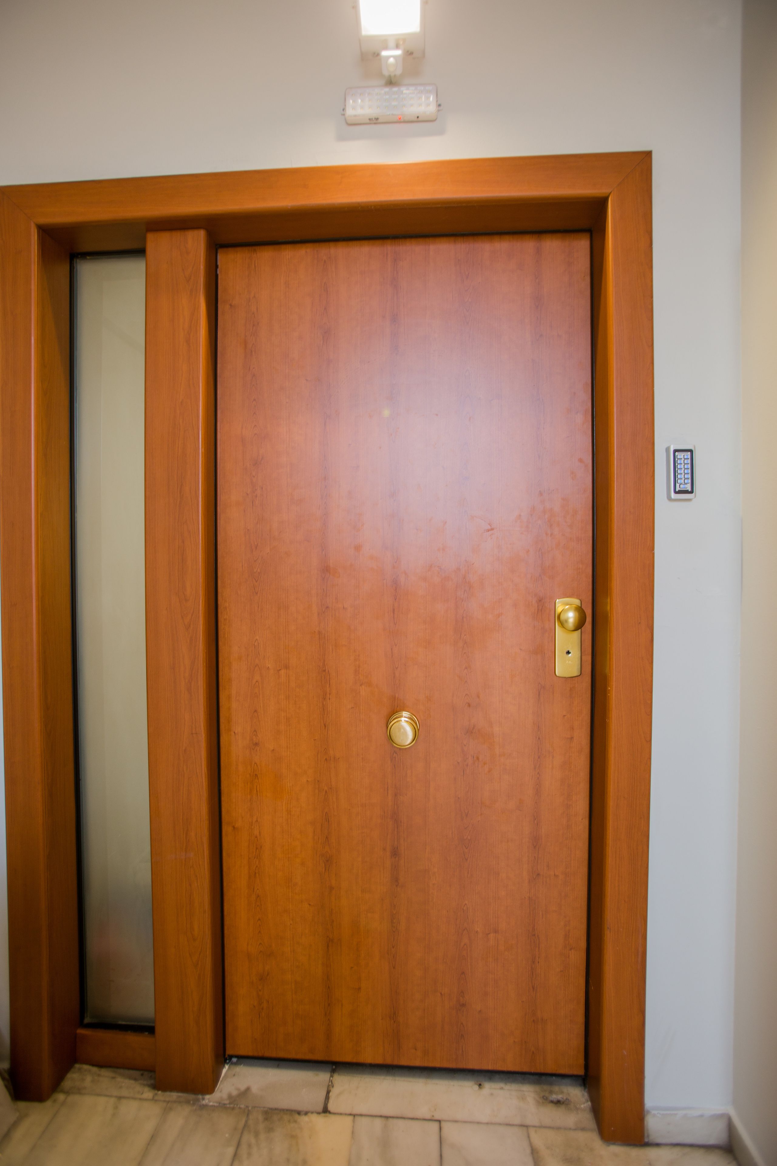A wooden door with a keyhole and a light switch above it.
