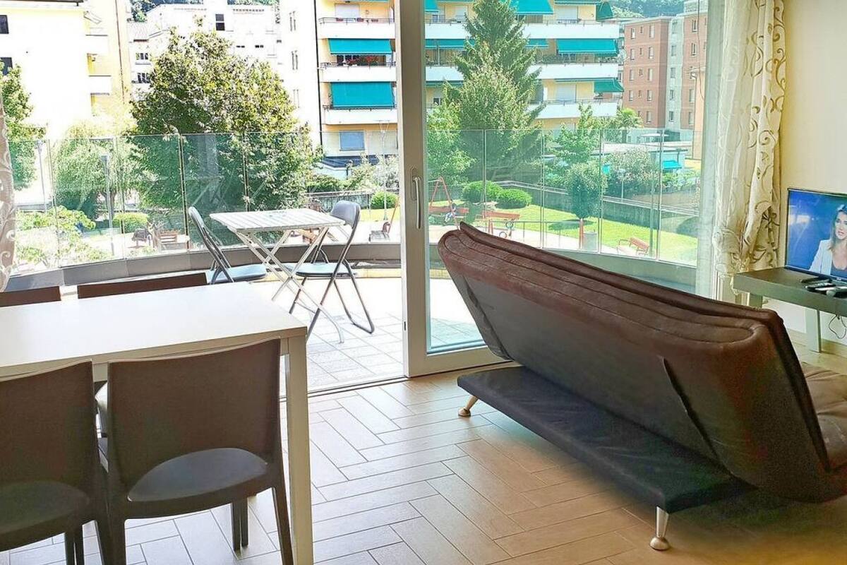A balcony with a dining table and chairs, a sofa, and a TV.