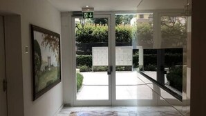 A hotel entrance with a glass door, a framed picture on the wall, and a signboard outside. - Roggia Apartments (Lugano)