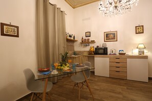 Eine kleine Küche mit Essbereich, ausgestattet mit einem Glastisch, Stühlen, einer Mikrowelle und einem Spülbecken.