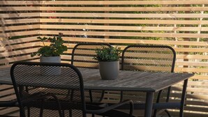 Une terrasse en bois avec une table et des chaises, entourée d’une clôture en bois.