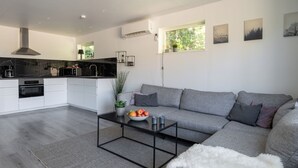 Un espace de vie moderne comprenant une cuisine, un canapé gris et une table basse sur laquelle sont disposés des fruits.