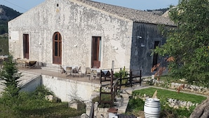 A rustic stone building with a terrace, outdoor seating, and a barrel labeled "TERRE DIABO."