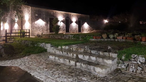 A stone building with a courtyard, steps leading up to the entrance, and potted plants.