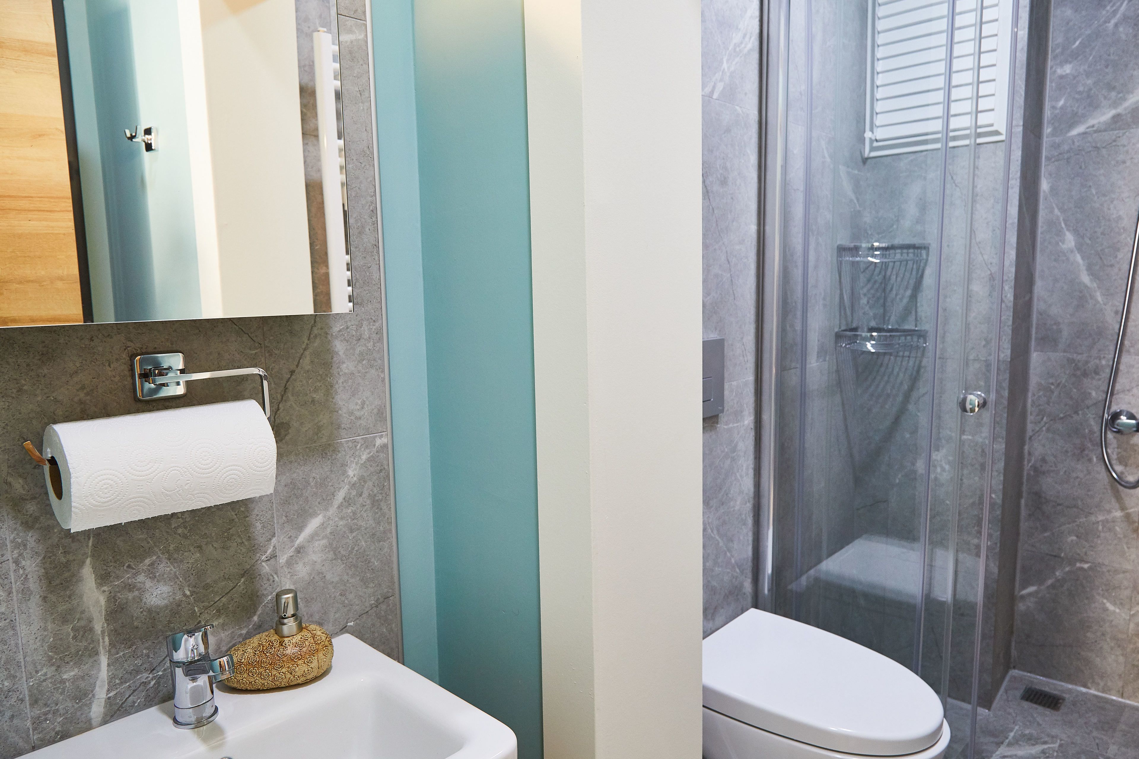 A bathroom with a sink, mirror, toilet, and shower.