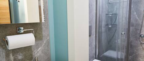 A bathroom with a sink, mirror, toilet, and shower.