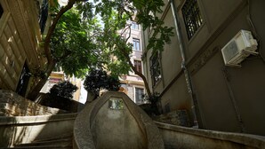 A stone staircase with a unique architectural design, leading up to a building with a window and an air conditioning unit. - No 8 Galata (Istanbul)