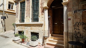 A building with a large wooden door, a stone facade, and a small outdoor seating area with potted plants. - No 8 Galata (Istanbul)