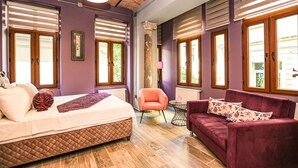 A bedroom with a bed, a purple wall, a wooden floor, a pink armchair, and a red sofa. - No 8 Galata (Istanbul)
