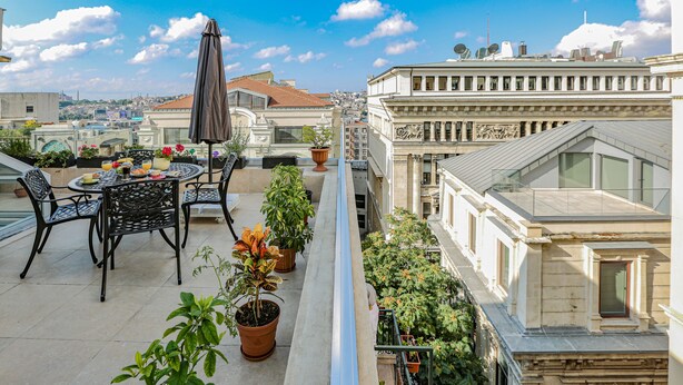 A rooftop terrace with a table, chairs, potted plants, and a view of the cityscape. - No 8 Galata (Istanbul)
