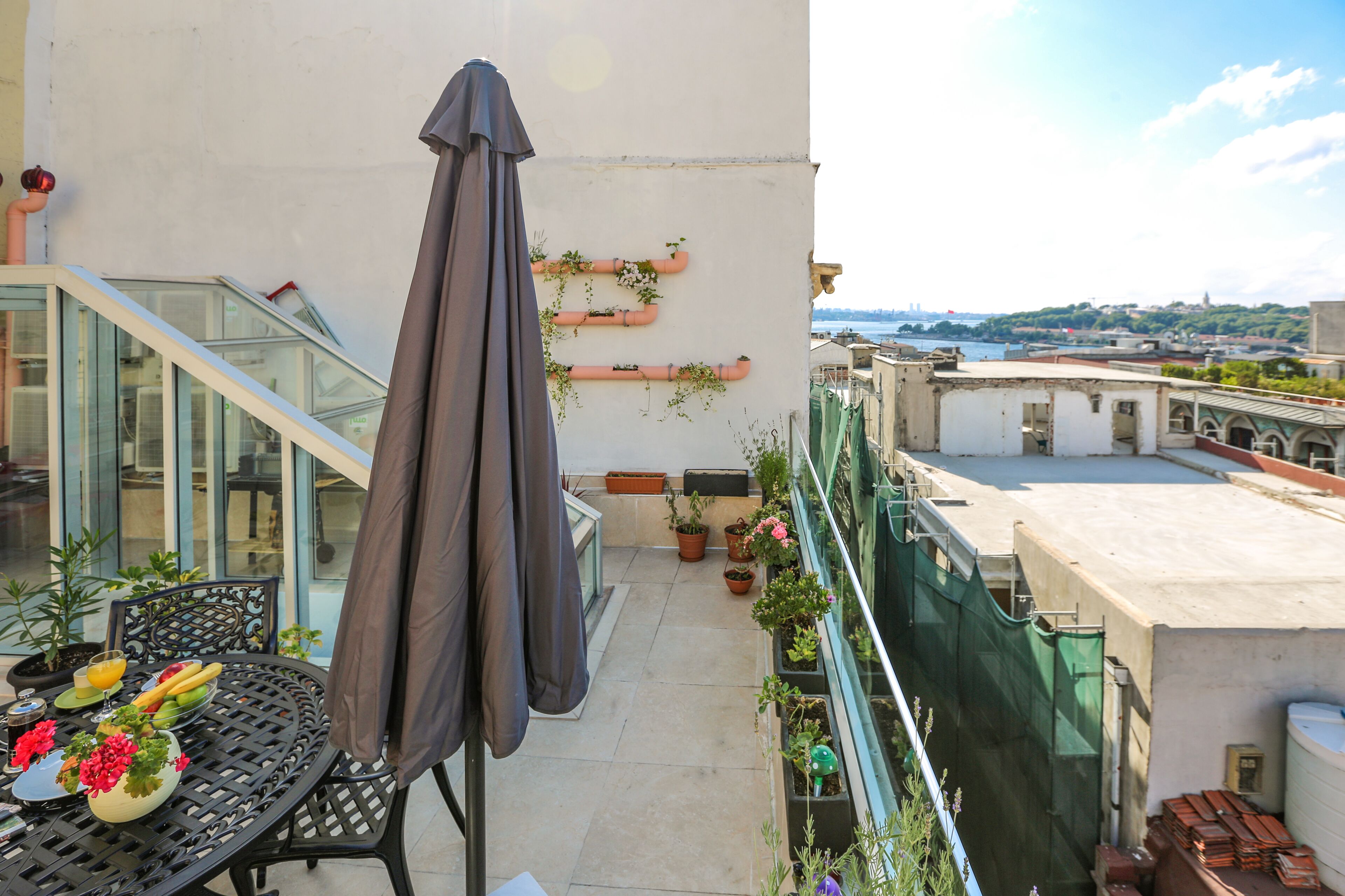 Une terrasse sur le toit, avec une table dressée pour le petit-déjeuner, des plantes en pot et une vue sur la ville.