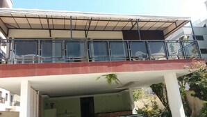 A building with a covered balcony area, a visible entrance, and a brick wall. - Pousada Casa da Regina (Guarujá)
