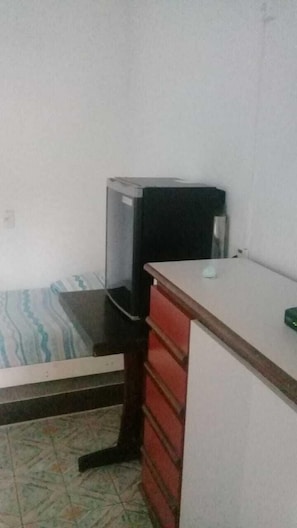 Ein kleines Zimmer mit einem Bett, einem Schreibtisch und einem Fernseher.