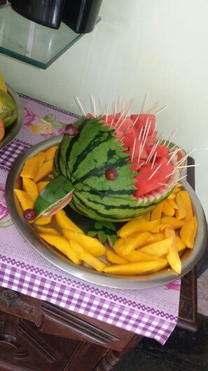 A bowl of fruit including watermelon, mango, and strawberries on a table with a checkered tablecloth. - Pousada Casa da Regina (Guarujá)