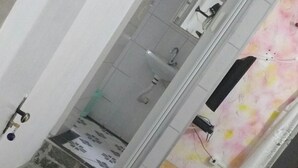 A staircase leading to a bathroom with a shower, a sink, and a mirror. - Pousada Casa da Regina (Guarujá)