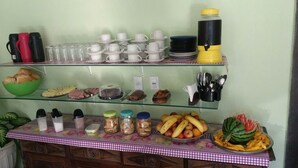 A buffet setup with various food items, utensils, and drink dispensers. - Pousada Casa da Regina (Guarujá)