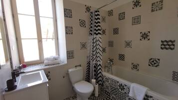 A bathroom with a toilet, sink, and bathtub. The walls are decorated with geometric and floral patterns.