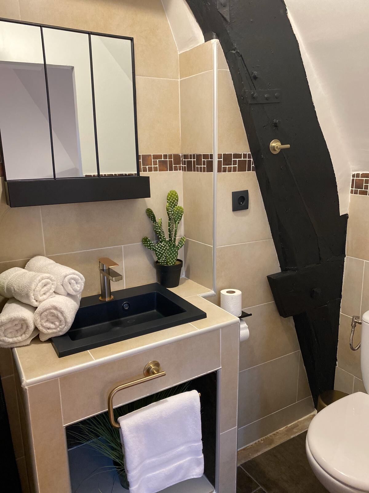 A bathroom with a sink, mirror, towel rack, and a shower area.