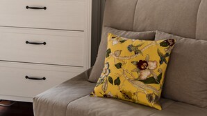 A room with a white dresser, a mirror with a floral frame, and a sofa with a yellow floral pillow. - Borgo Pinti Apartment (Florence)