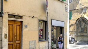 A building with a wooden double door, a shop entrance, and a street sign. - Borgo Pinti Apartment (Florence)