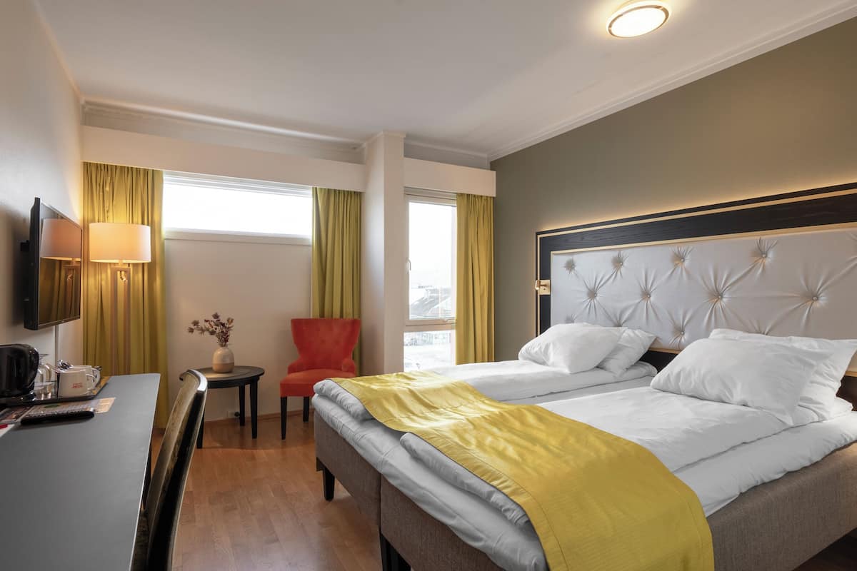 A hotel room with a bed, a desk, a chair, and a television.