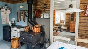 A rustic kitchen with a wood stove, copper pots, and vintage kitchenware. - Thon Hotel Sortland (Sortland)