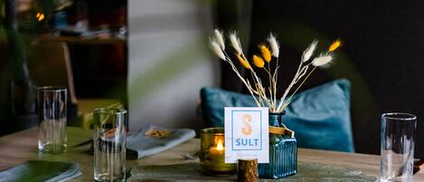 A dining table set with glasses, a candle, and a sign indicating a restaurant named 'SULT Grill House'.