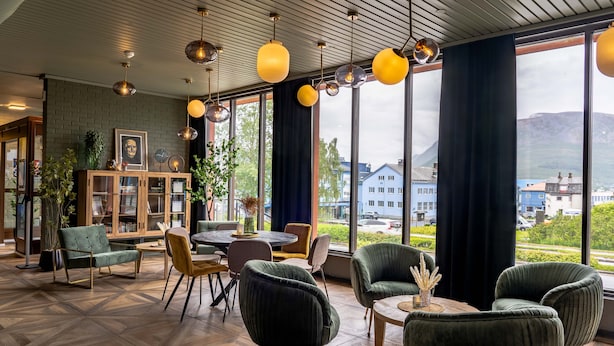 A modern interior with a wooden floor, green upholstered chairs, a round table, and a bookshelf. - Thon Hotel Sortland (Sortland)