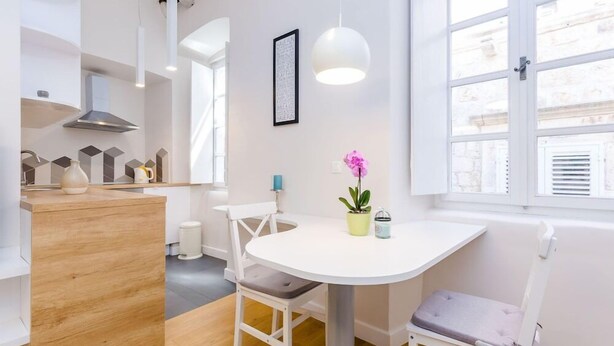 Een moderne keuken met een witte tafel, stoelen en hanglampen.