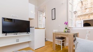 Een moderne woonkamer met een flatscreen televisie, een houten eettafel en een gezellige bank.