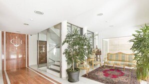 A modern lobby with a marble floor, a staircase, a reception desk, and a seating area with a patterned rug. - Prestige Du Lac Apartments (Lugano)