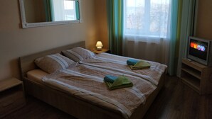 Een hotelkamer met een bed, televisie, lamp en raam met gordijnen.
