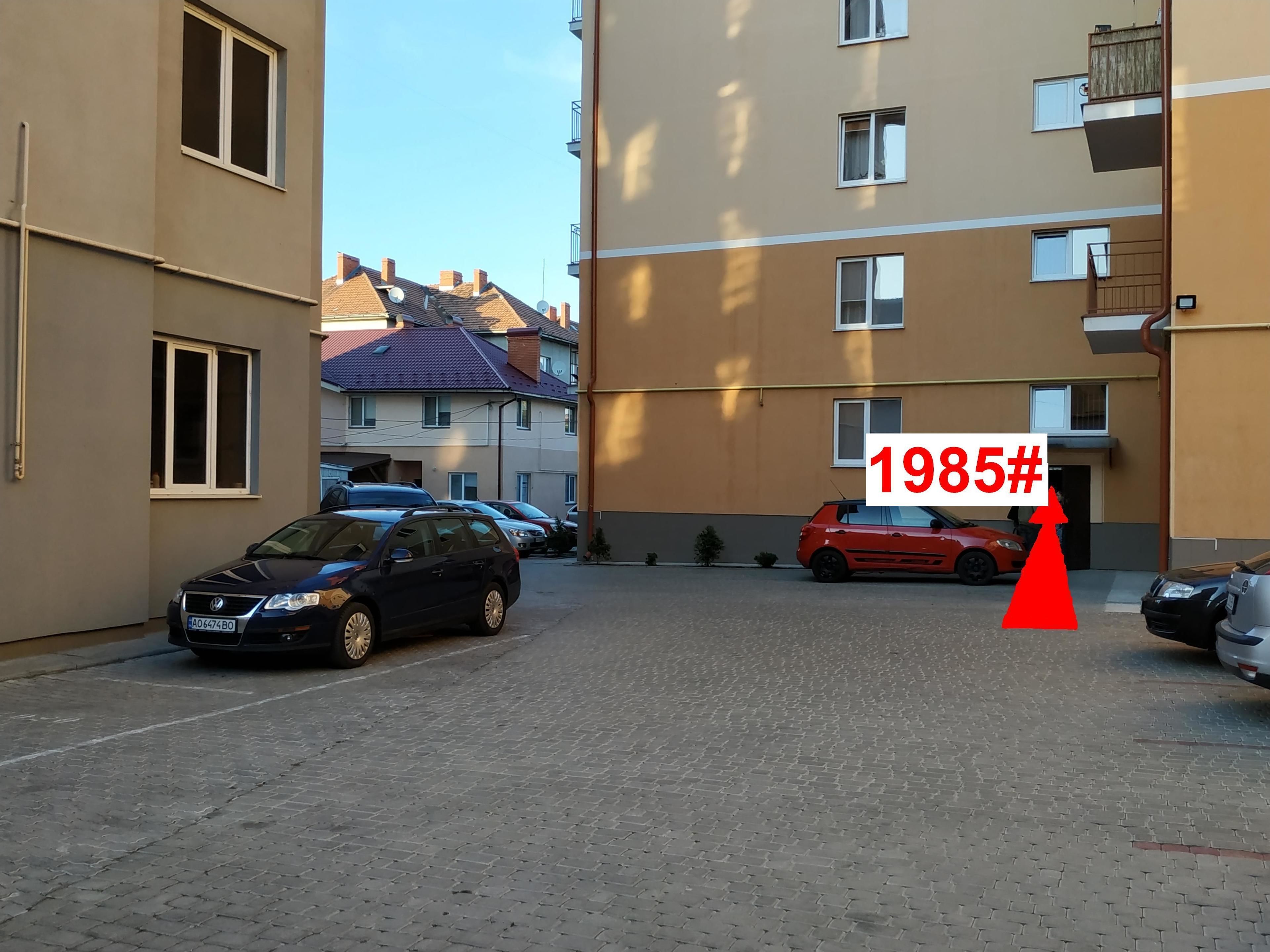 A residential street with parked cars and apartment buildings.