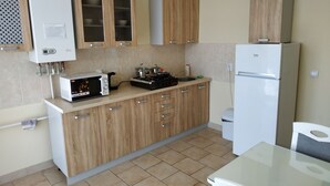 Een moderne keuken met houten kastjes, een ingebouwde magnetron, een gasfornuis en een witte koelkast.