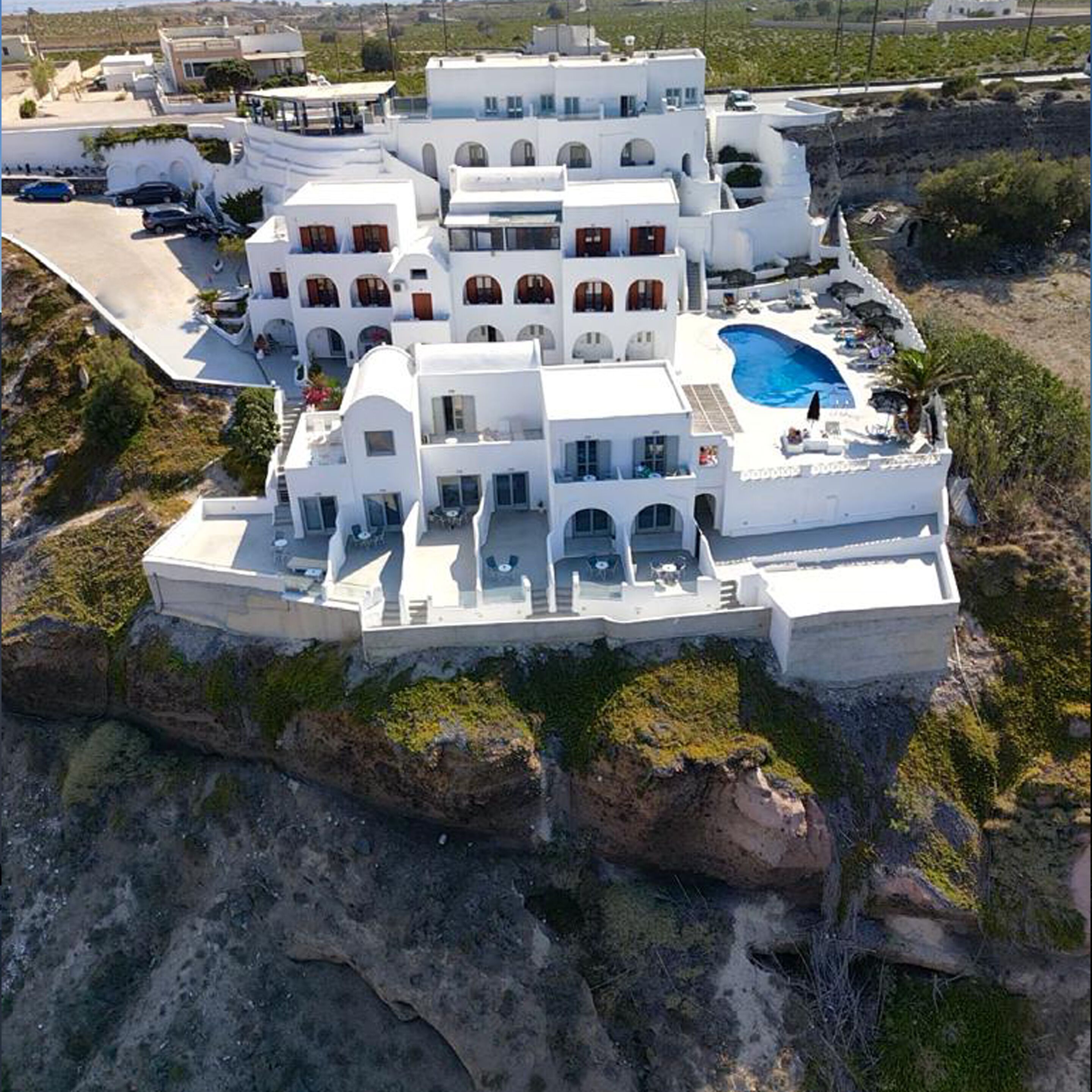 A white, multi-story building with a rooftop pool and outdoor seating area.