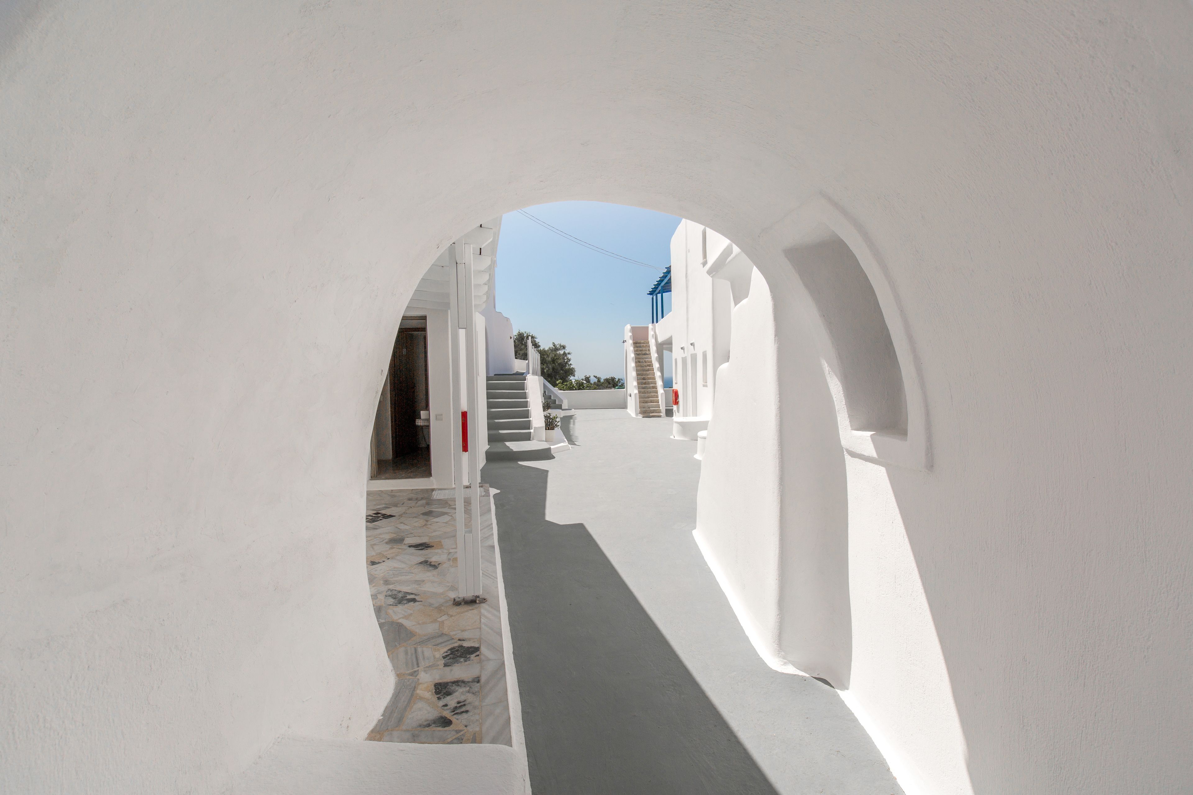 A narrow, white-walled corridor with a tiled floor and a staircase leading to a higher level.
