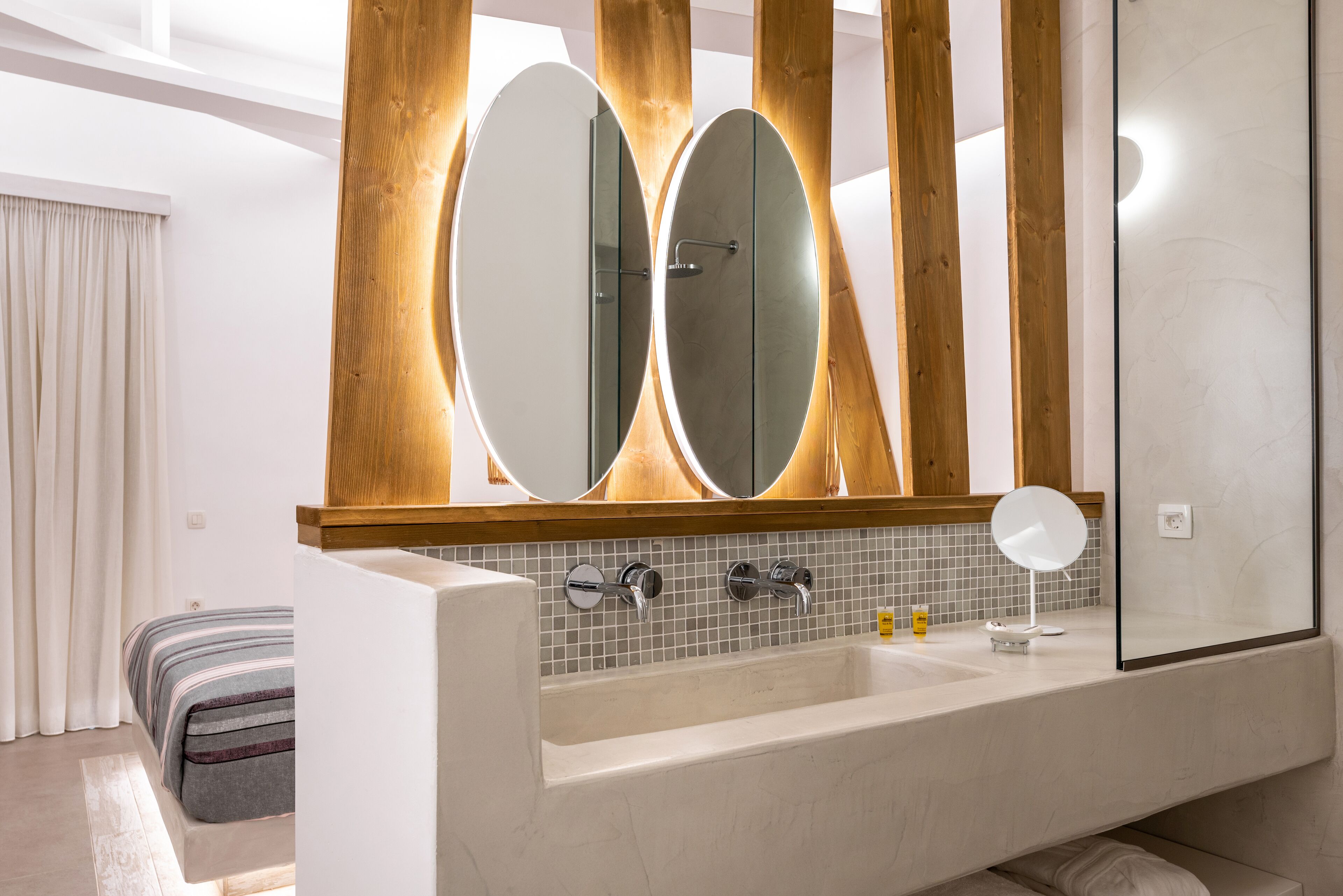 Un baño moderno con una bañera grande, dos espejos y una pared de detalles en madera.