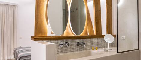 Un baño moderno con una bañera grande, dos espejos y una pared de detalles en madera.