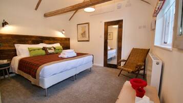 A bedroom with a bed, a chair, a radiator, and a window.