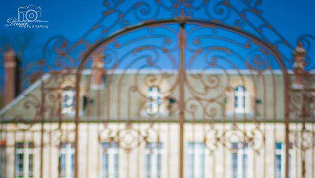 A person sitting on a bench facing a large, ornate gate. - Le Chateau de Plessier-Rozainvillers (Le Plessier-Rozainvillers)