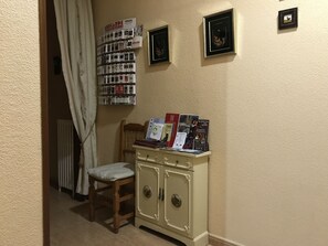 A corner of a room with a radiator, a wooden chair, a cabinet with a mirror, and a wall with framed pictures and a bulletin board. - Hostal Internacional (Madrid)