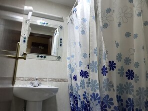 A bathroom with a sink, mirror, and shower curtain. - Hostal Internacional (Madrid)