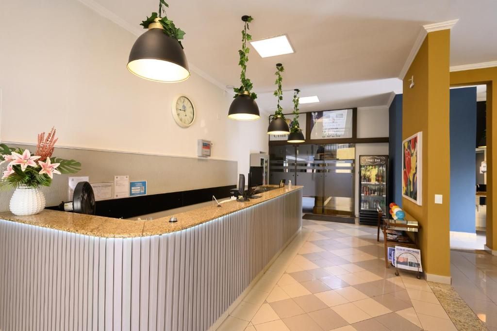 A hotel reception area with a counter, a clock, and a refrigerator.