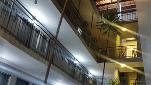 A multi-level building with balconies, potted plants, and a central open area. - Universitário Hotel (Itapetininga)