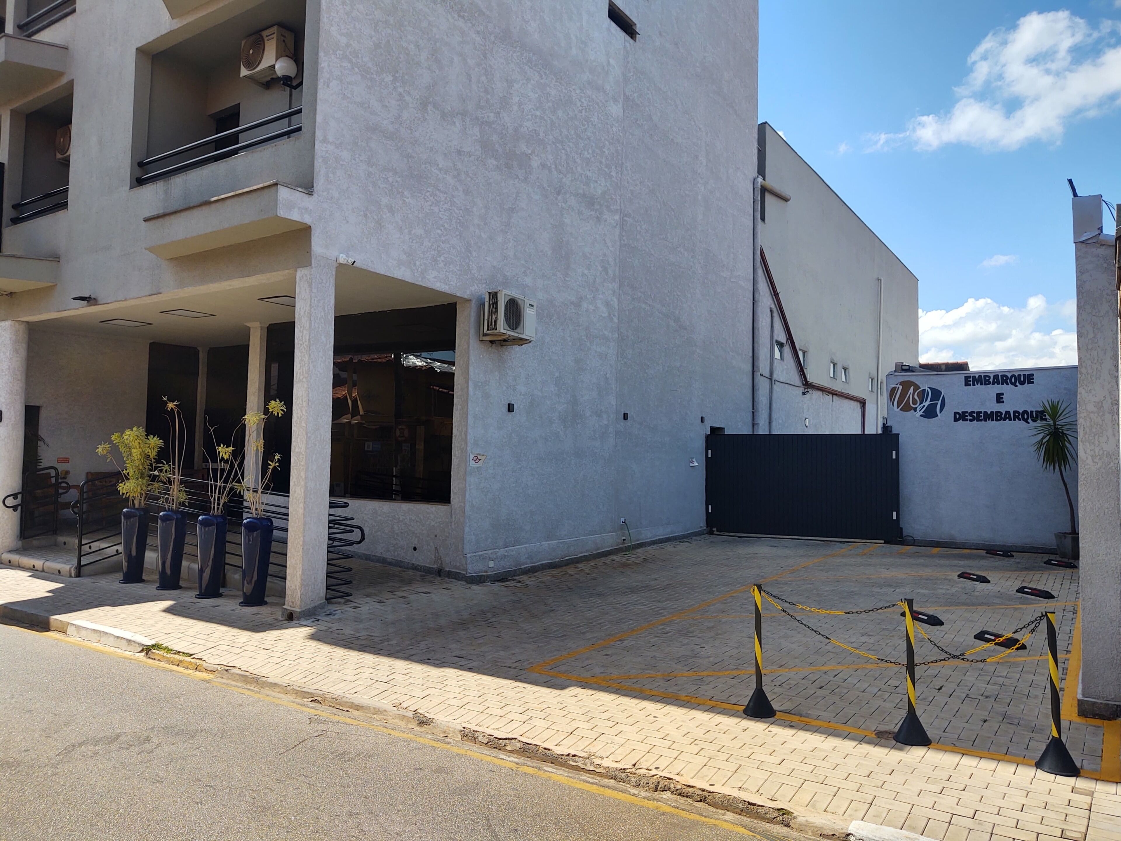A building with a gated entrance, outdoor seating, and potted plants.