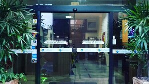 A hotel entrance with glass doors, a sign for 'Porta de Corretor', and a 'Unilodge' logo. - Universitário Hotel (Itapetininga)