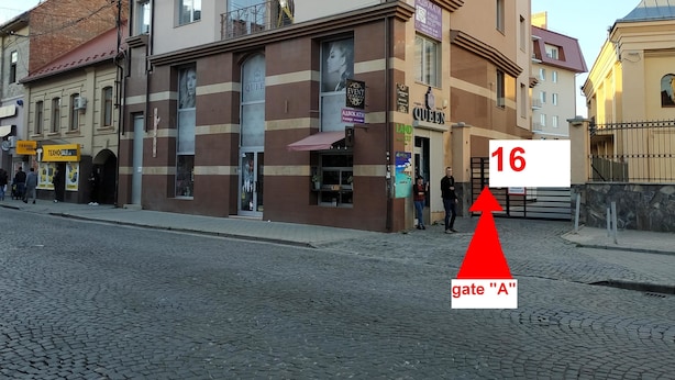 Un edificio de varios pisos con un letrero que dice 'Queen' y un cartel de 'TEXHO SALE'.