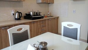 Una cocina moderna con armarios de madera, estufa a gas y una mesa de comedor blanca.